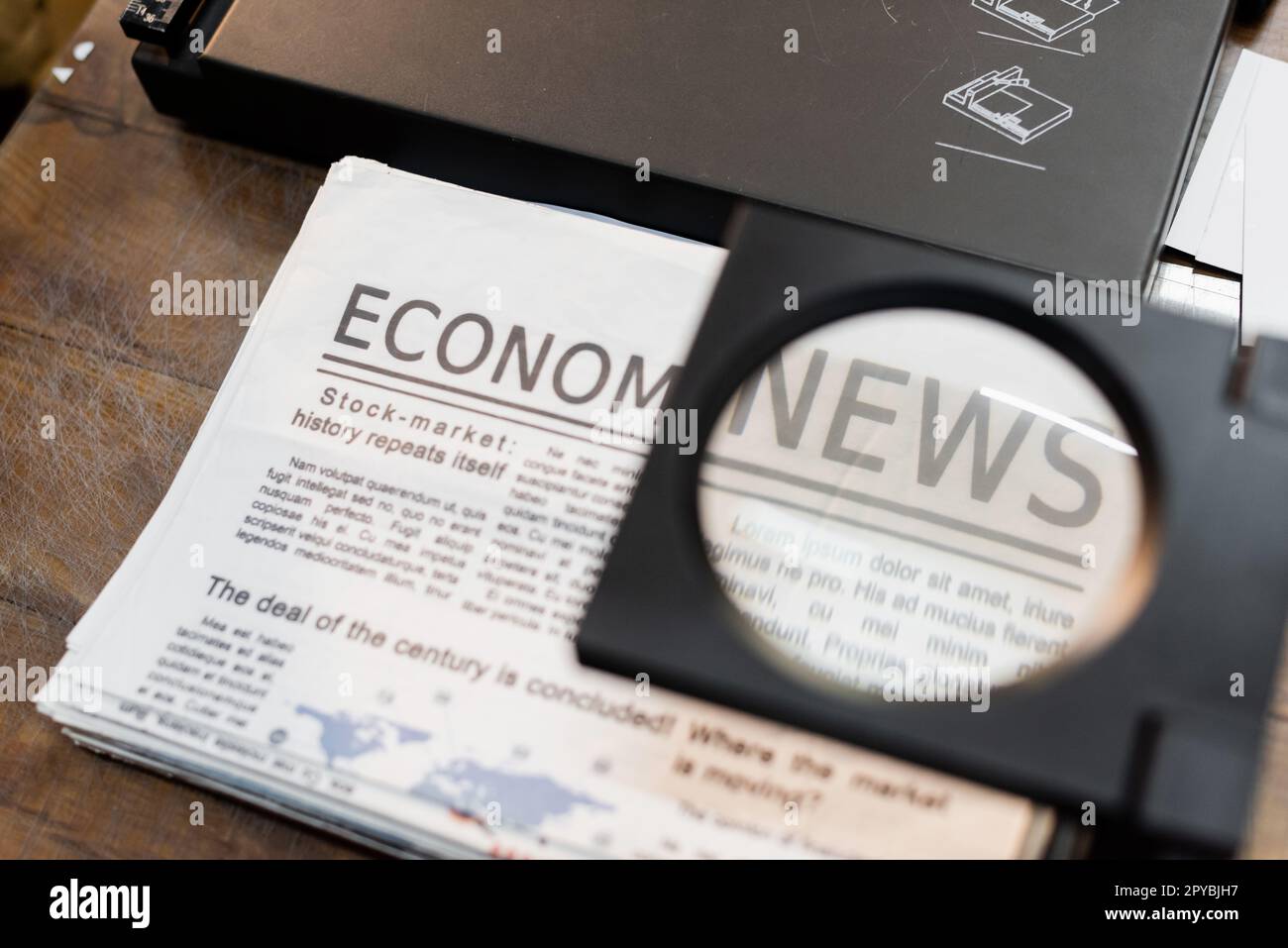 Lupe über Zeitungen mit Wirtschaftsnachrichten in der Druckerei, Börsenbild Stockfoto