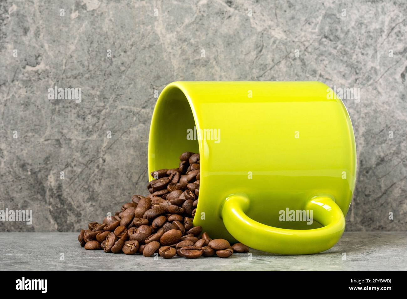 Kaffeebohnen werden aus einer grünen Tasse gegossen Stockfoto