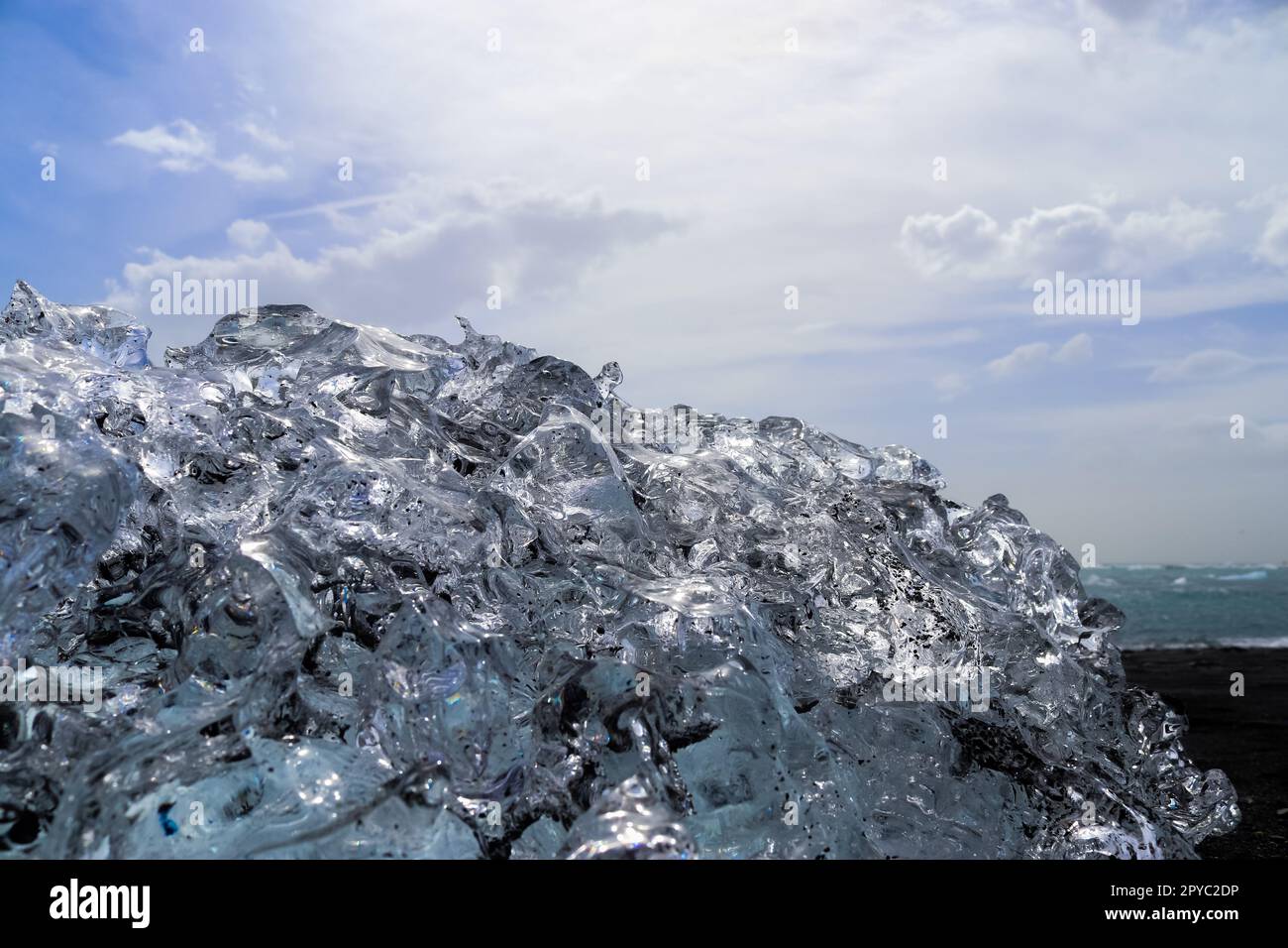 Diamond Beach in Island mit blauen Eisbergen, die auf schwarzem Sand schmelzen und Eis, das mit Sonnenlicht glitzert. Stockfoto