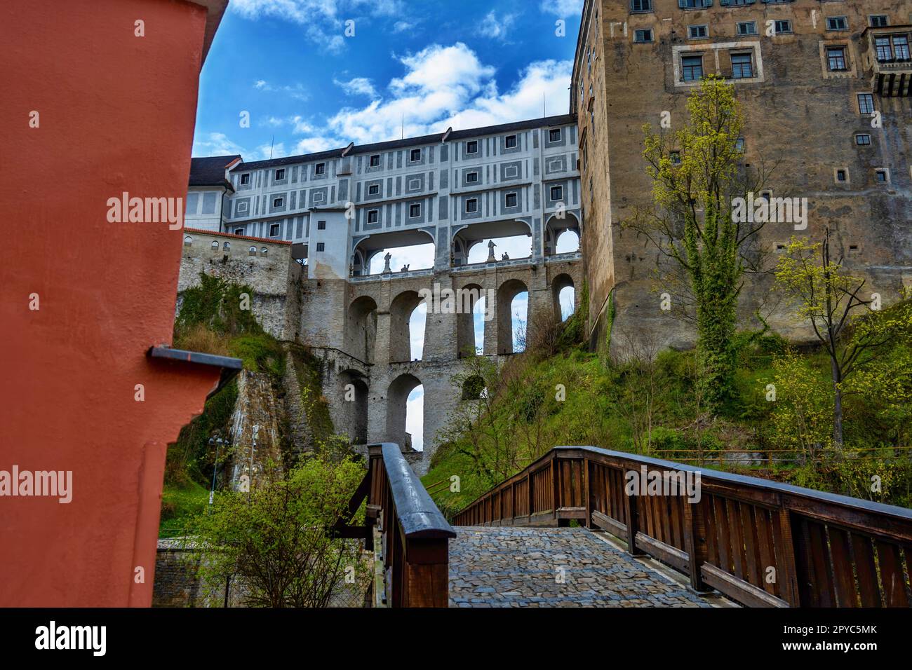 Schloss Cesky Krumlov und berühmte Mantle-Brücke (monumentale Arkadenbrücke) im Hintergrund, kleine Brücke im Vordergrund. Stockfoto