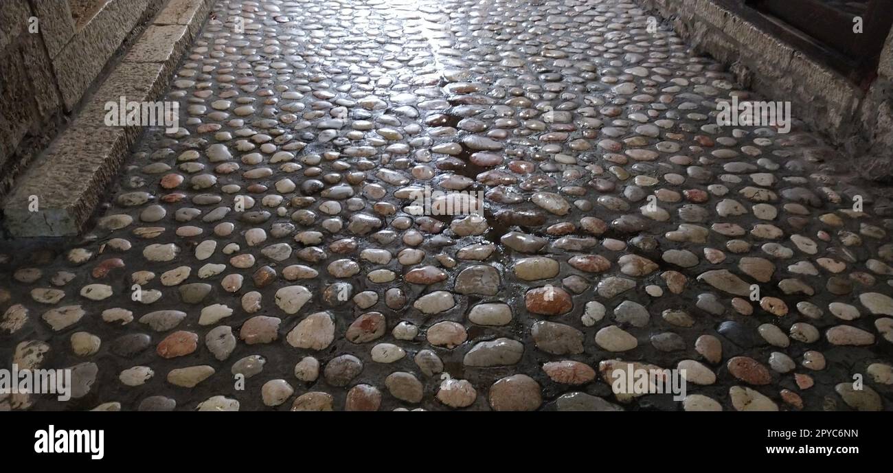 Pflastersteine aus runden, hellen Steinen, ähnlich wie Marmor. Gepflasterter Platz in der Altstadt von Sarajevo, Bosnien und Herzegowina. Wunderschöne nasse, glänzende Steine nach Regen. Stockfoto
