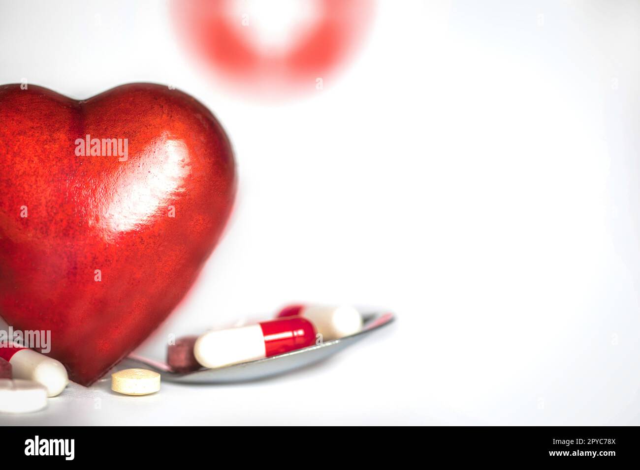 Rotes Herz mit Medikamentenpillen isoliert auf weißem Hintergrund, Konzept Drogen, Medizin, Gesundheit, medizinische Versorgung mit Copy Space Hintergrund Stockfoto