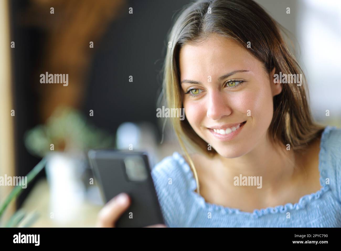 Ein glücklicher Teenager, der in einem Haus sein Handy überprüft Stockfoto