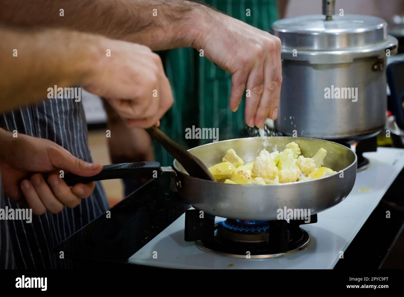 Traditionelle Zubereitung von indischem Essen Aloo gobi (Kartoffeln mit Blumenkohl) mit einer Gaspfanne. Bild der traditionellen indischen Küche aus frischem Ingre Stockfoto