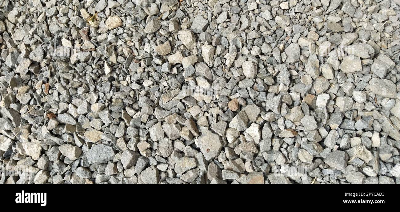 Großer zerkleinerter Stein in hellgrauer Farbe. Kleine Steine als Hintergrund Stockfoto