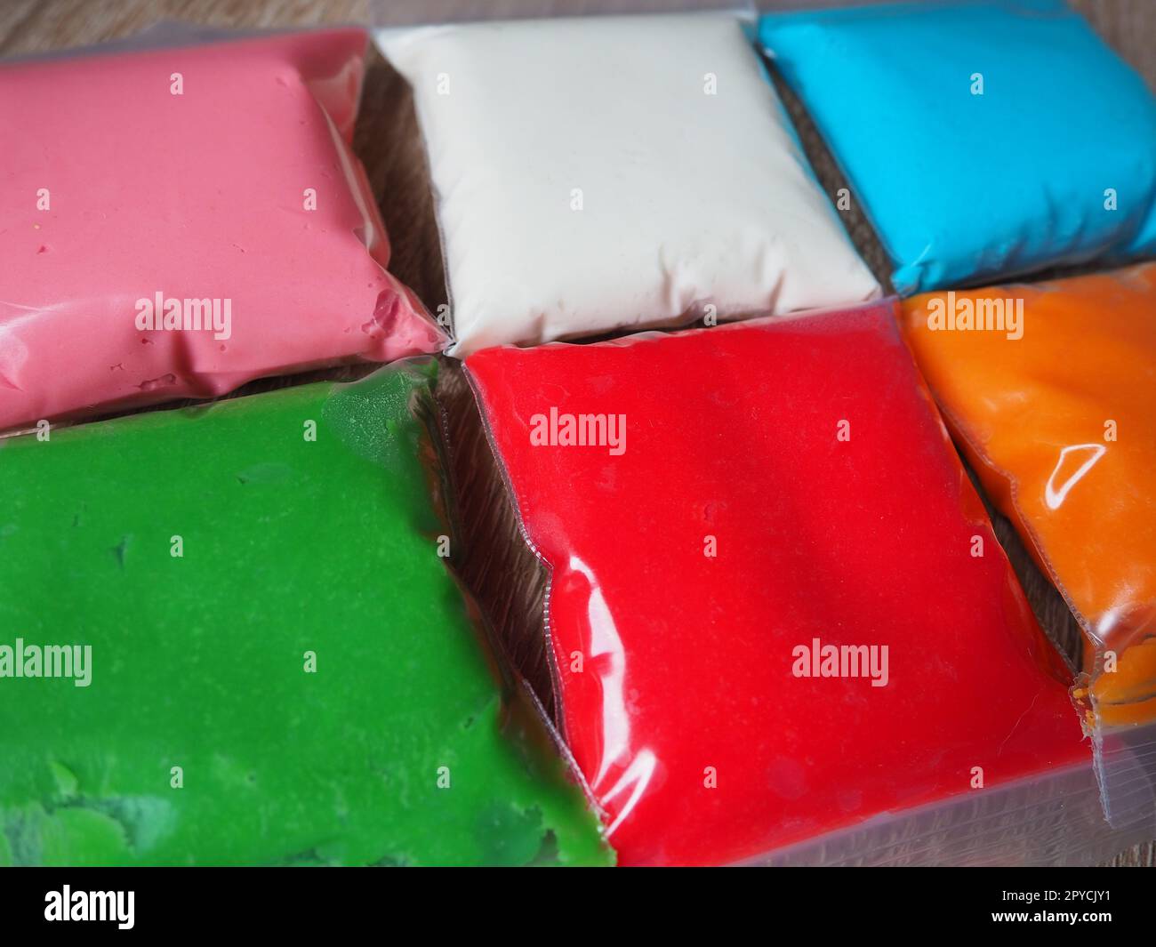 Farbenfrohe Kinderplastik auf weißem Hintergrund, farbenfroher Teig-Modelliermist. Verpackung von gefärbtem Weichplastin in Plastikbeuteln Stockfoto