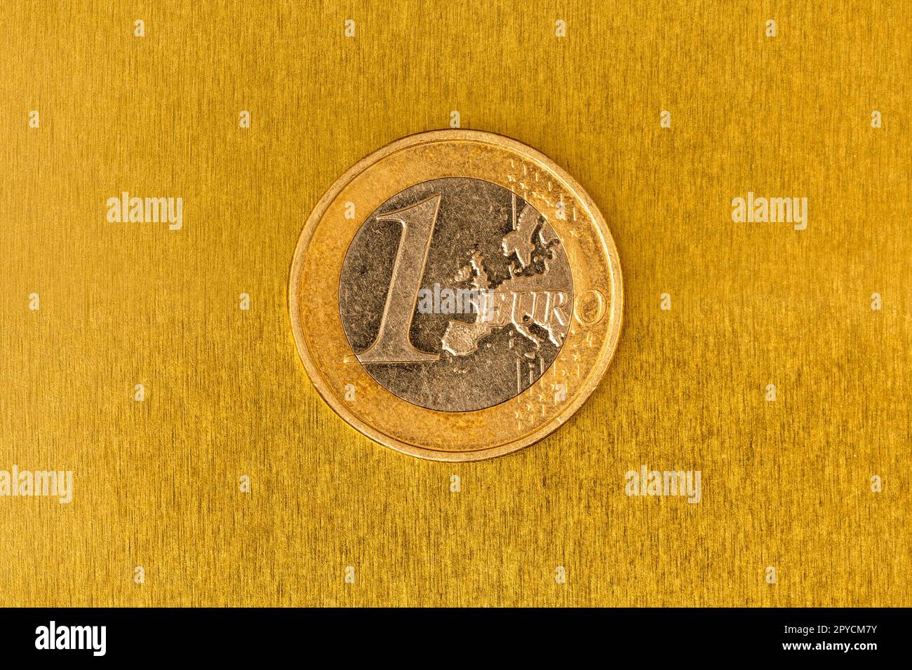 Eine Euro-Münze auf dem gelb glänzenden metallischen Hintergrund Stockfoto