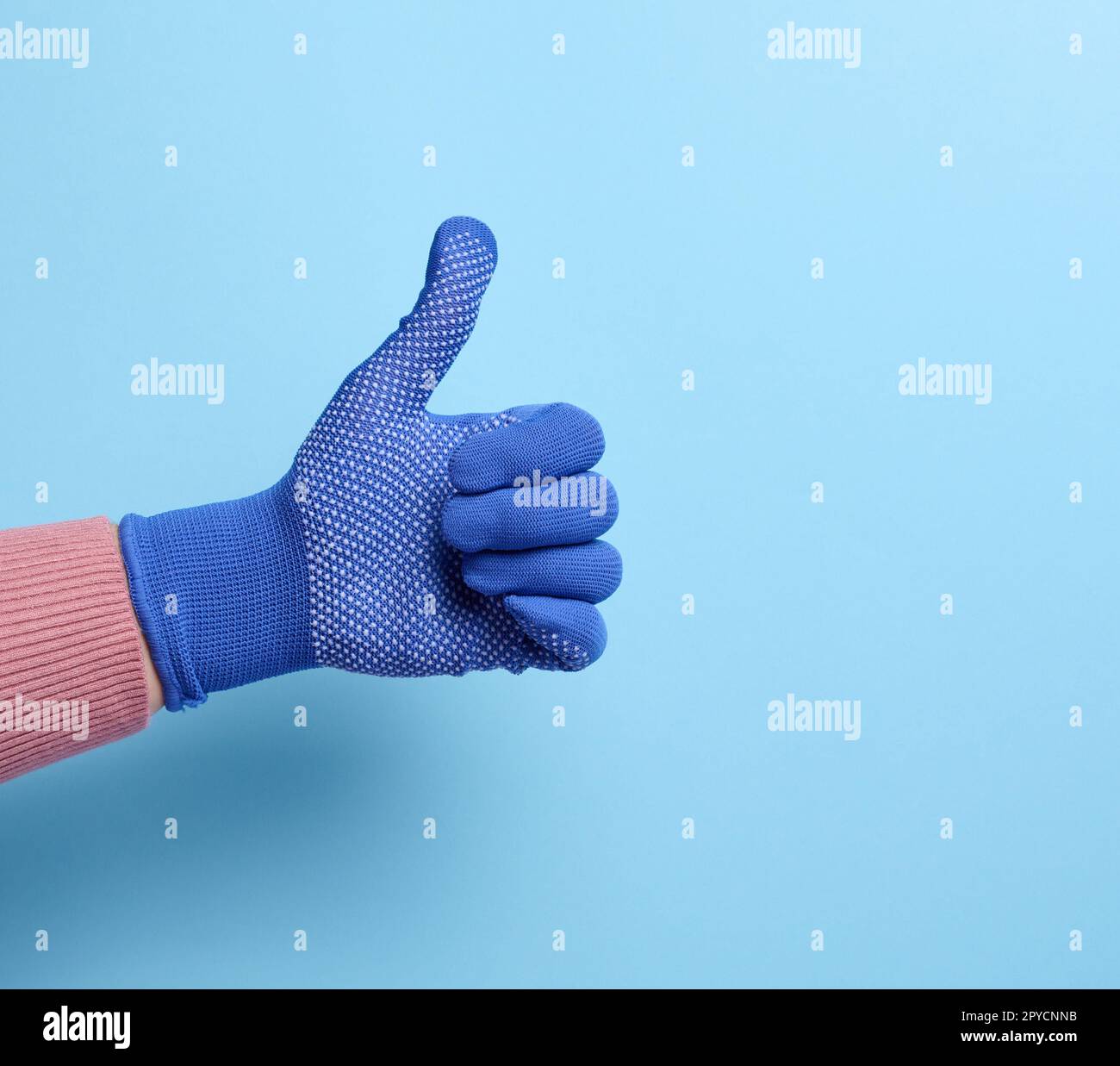 Weibliche Hand in blauem Arbeitshandschuh zeigt die Geste wie auf blauem Hintergrund Stockfoto