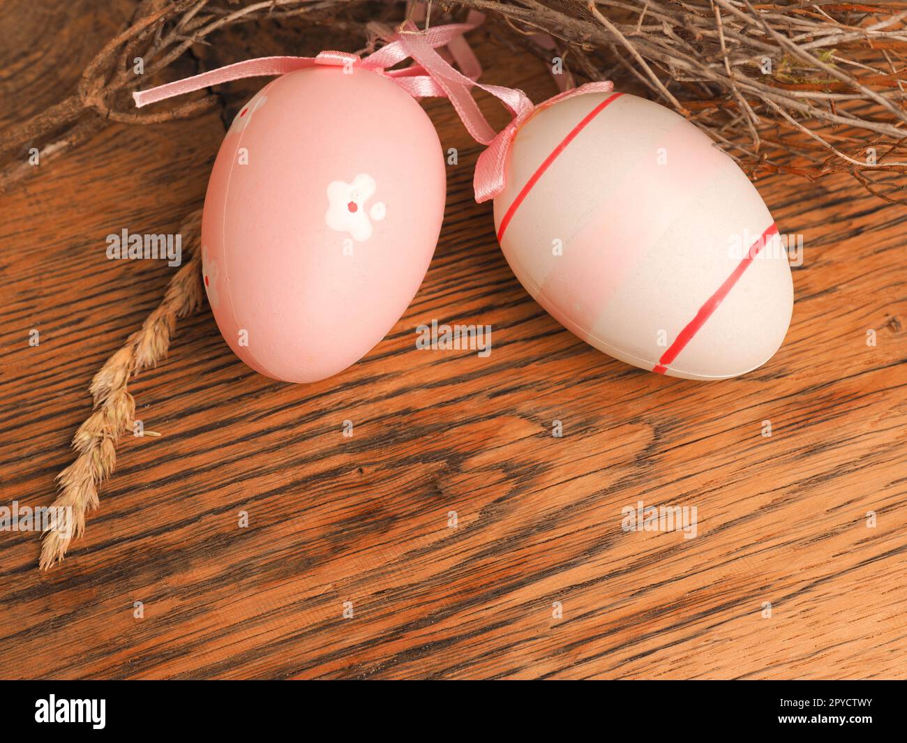 Rosafarbene Ostereier mit Dekoration auf einem rustikalen Holztisch Stockfoto