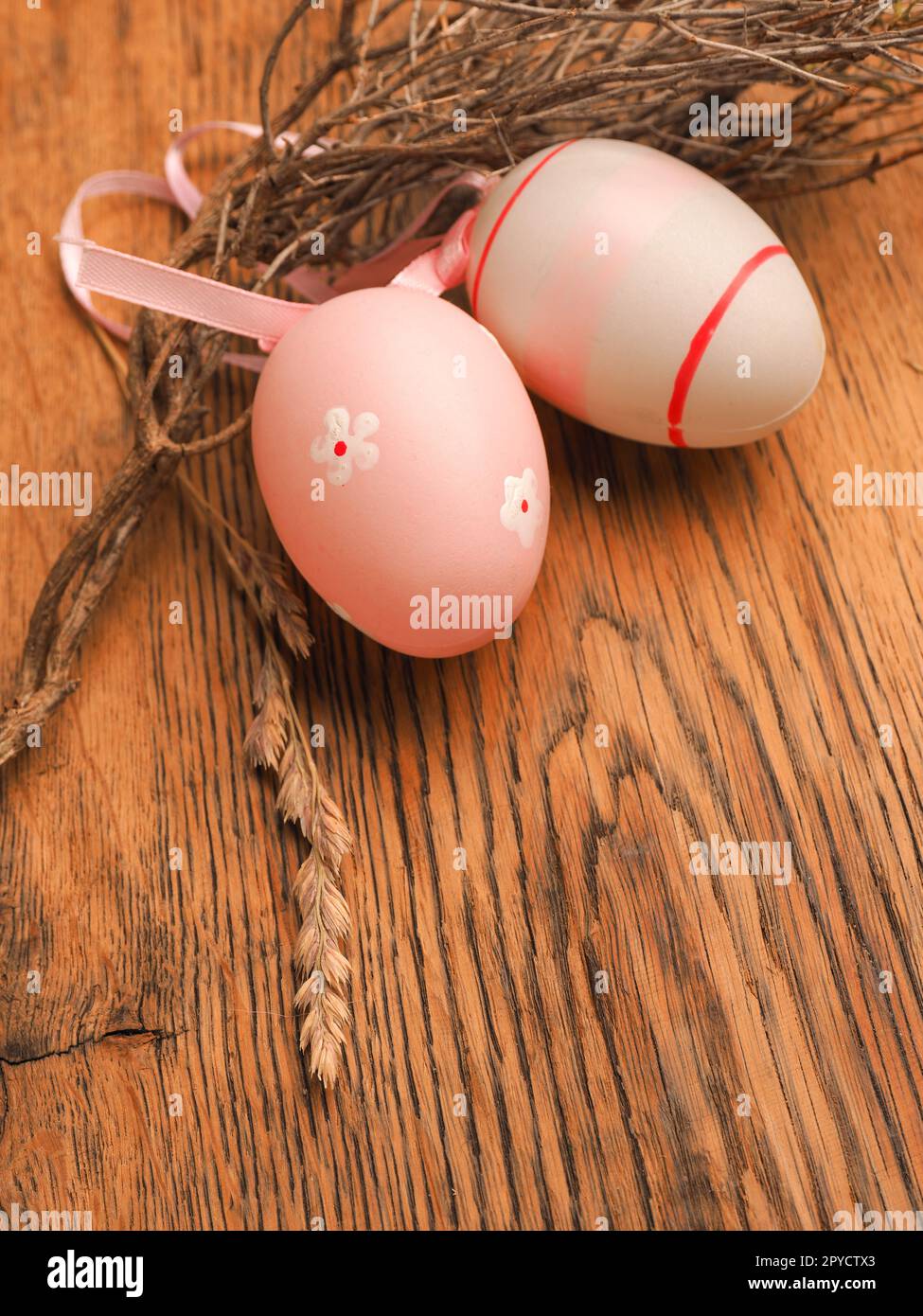 Rosafarbene Ostereier mit Dekoration auf einem rustikalen Holztisch Stockfoto