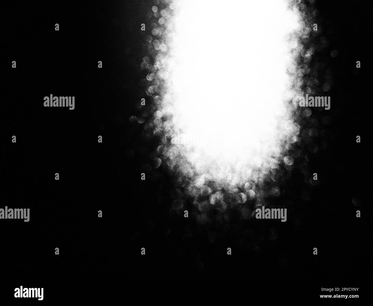 Weißes Bokeh und Strahl auf schwarzem Hintergrund. Verschwommenes Licht von oben auf dunkler Oberfläche. Nacht- oder Weltraum-Thema. Bokeh für die Feiertage. Vereinigung für einen fliegenden Meteoriten. Abstraktes Thema Stockfoto