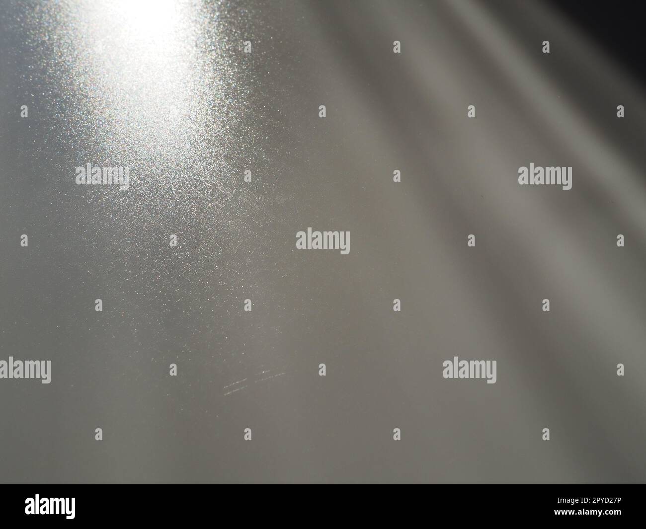 Diagonale Lichtstrahlen auf grauem Hintergrund. Verschwommenes abstraktes Hintergrundlicht, Lichtaustritt. Beleuchtung der Seitenfläche. Kleine Funken und Glühen. Glänzen, glänzen oder Blenden. Links oben rechts unten. Stockfoto