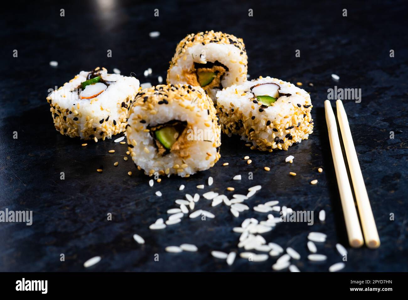 Sushi auf einer schwarzen Tischplatte mit Holzstäbchen. Japanisches Essen im Restaurant. Stockfoto