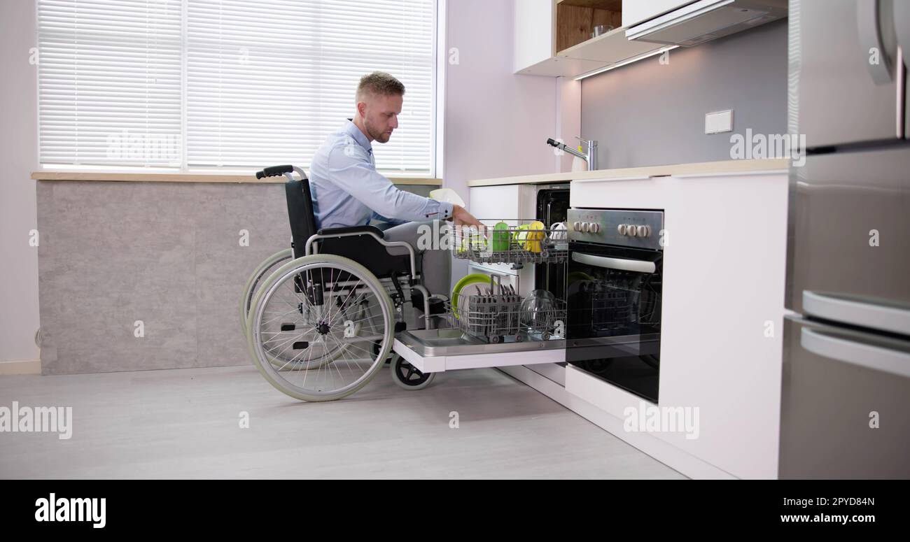 Behinderte Person Im Rollstuhl Mit Geschirrspüler Stockfoto