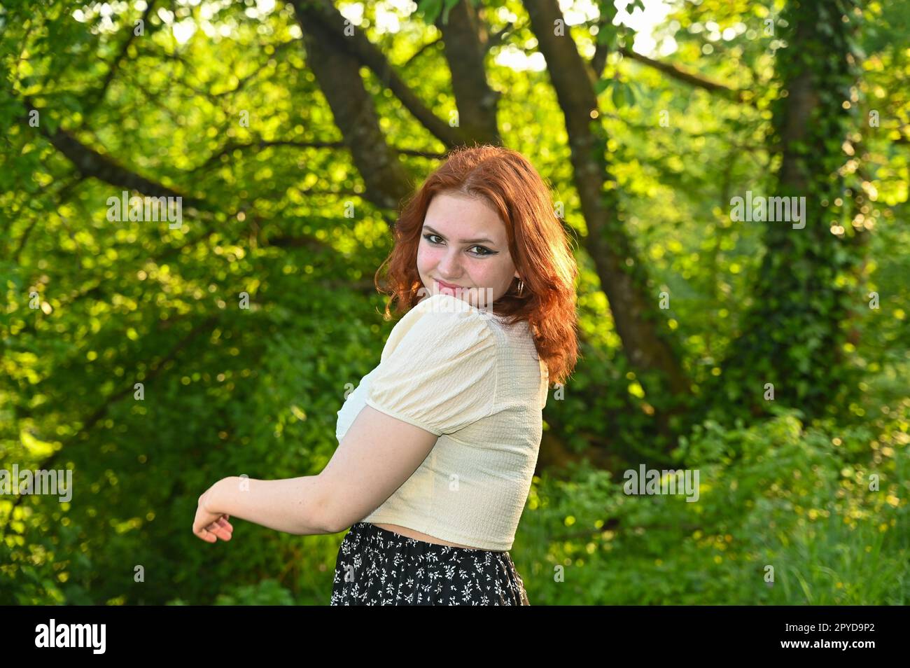 Eine junge, hübsche rothaarige Frau in grüner Natur Stockfoto