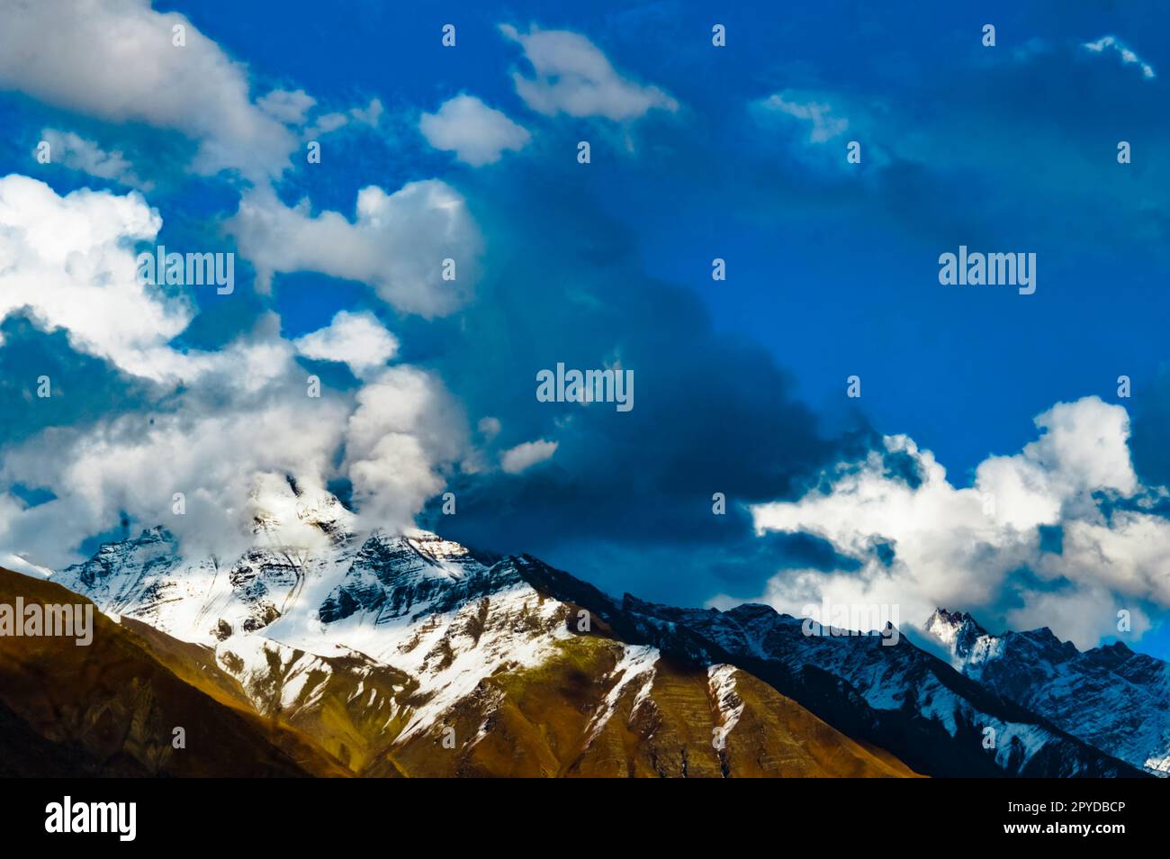 Schneebedeckte Bergspitze mit blauem Himmel und schwimmenden Wolken. Dramatische Naturlandschaft. Yungthum Valley Sikkim Indien Südasiatisch-pazifischer Raum Stockfoto