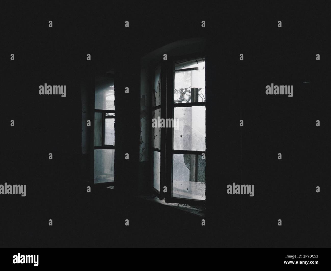 Beängstigende Fenster. In einem verlassenen Haus. Blick auf kaputte Fenster ohne Vorhang. Grunge-Szene. Das Licht scheint durch alte Holzrahmen mit Glasscherben. Das Konzept von Verlassenheit und Nützlichkeit Stockfoto