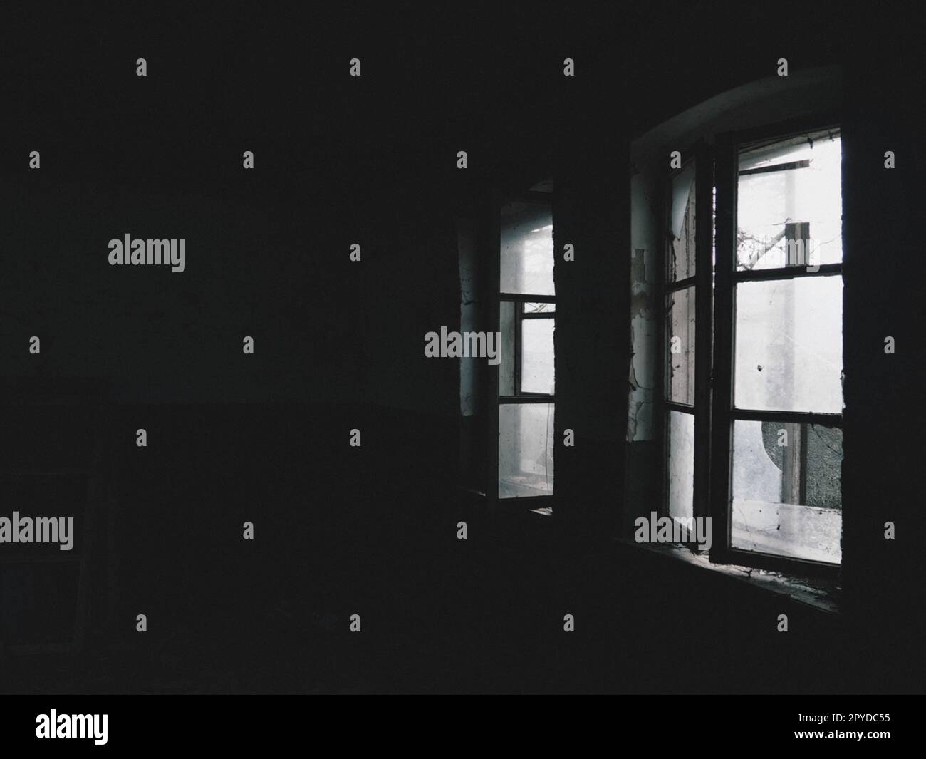 Beängstigende Fenster. In einem verlassenen Haus. Blick auf kaputte Fenster ohne Vorhang. Grunge-Szene. Das Licht scheint durch alte Holzrahmen mit Glasscherben. Das Konzept von Verlassenheit und Nützlichkeit Stockfoto