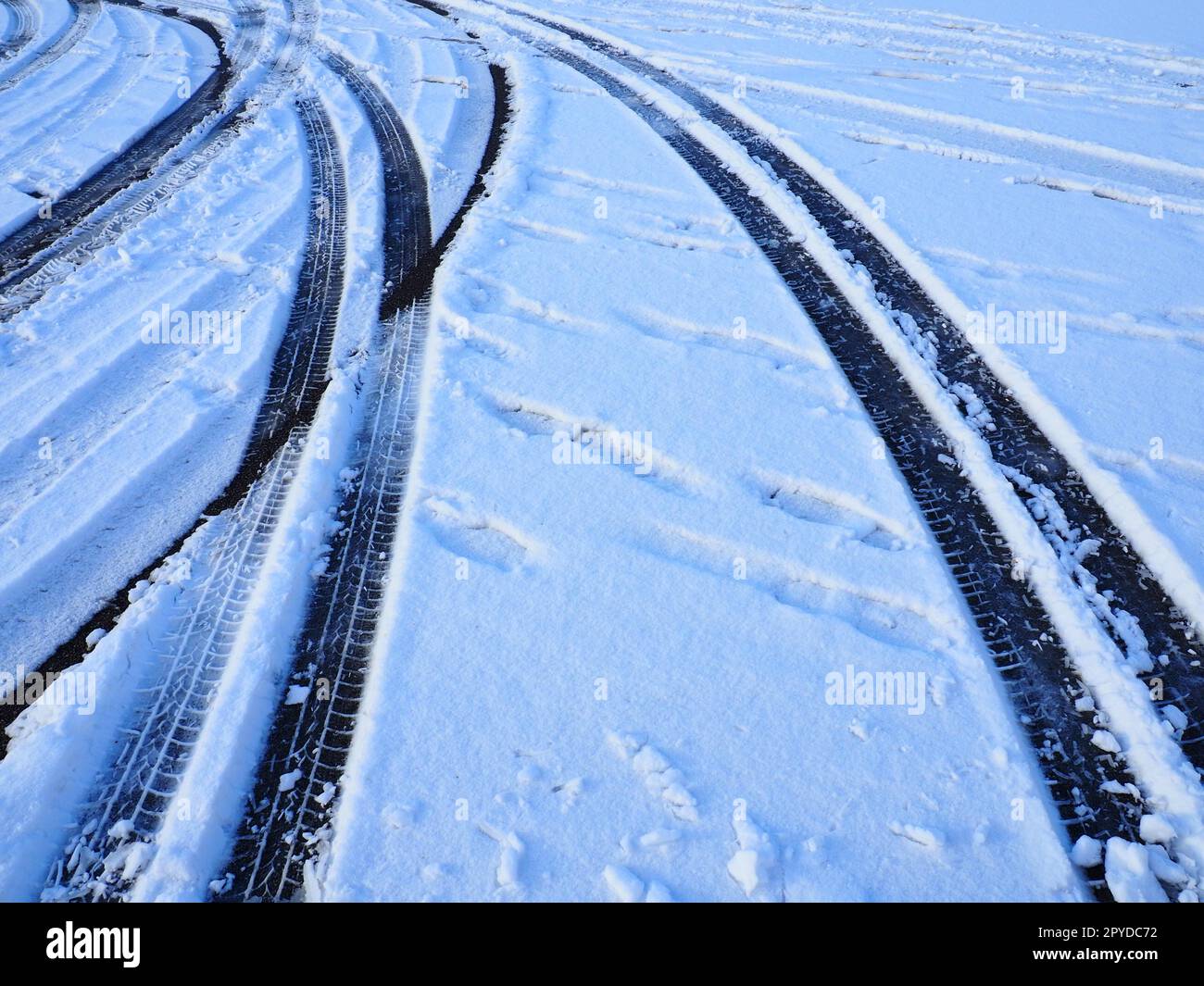 Schneeverwehungen am Straßenrand. Schlechtes Wetter und Verkehr. Schnee auf Asphalt. Schwierige Fahrbedingungen. Winterschlamm auf der Straße. Bremsweg eines Autos. Stockfoto