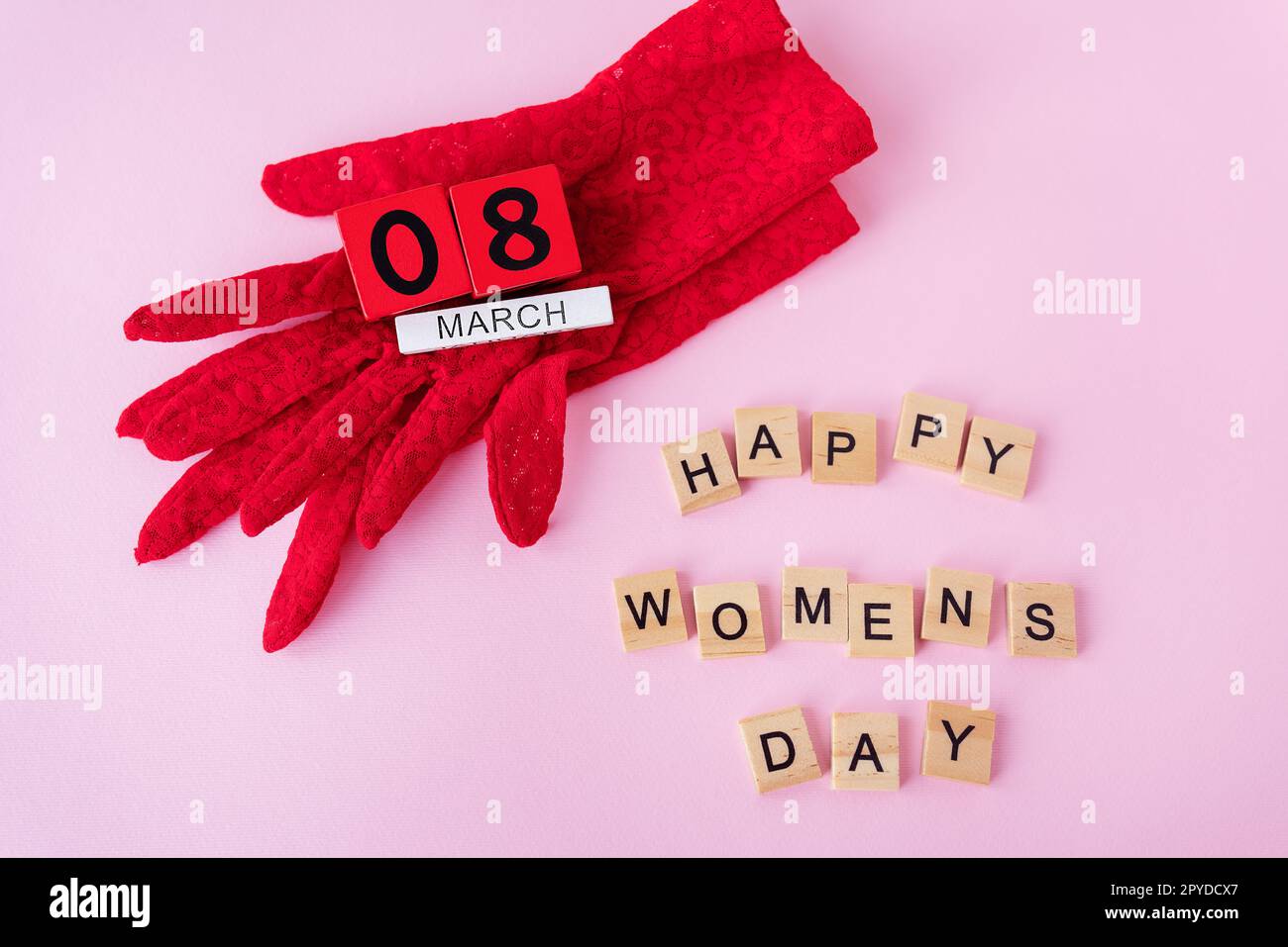 Wunderschöne rote Spitzenhandschuhe, auf denen Holzwürfel mit der Inschrift März 8, die Inschrift des glücklichen Frauentages. Karte für den Feiertag, Frauentag. Stockfoto