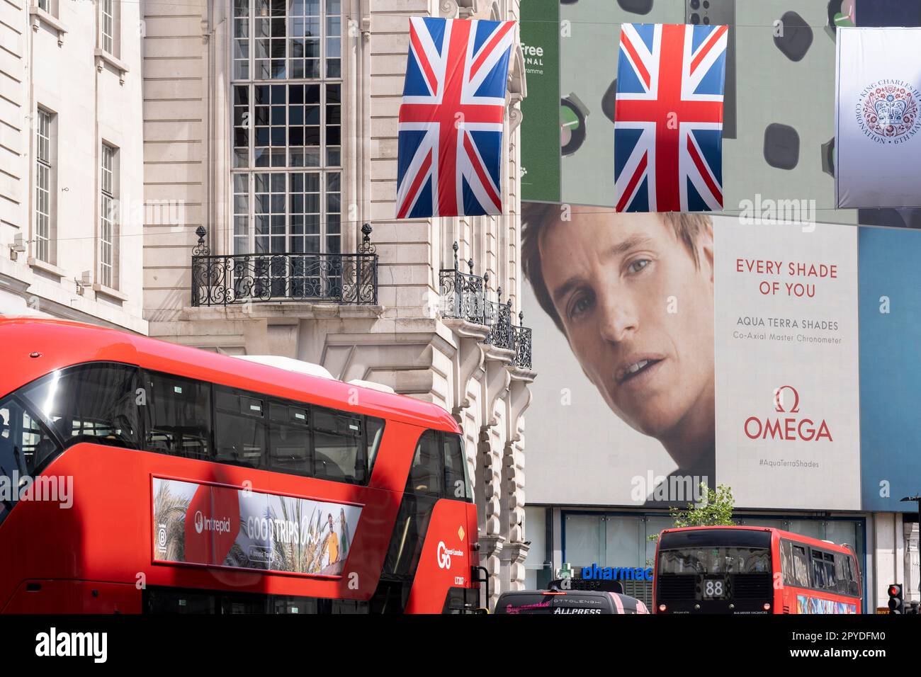 Nur vier Tage vor der Krönung von König Karl III., nach dem Tod seiner Mutter, Königin Elizabeth II. Im letzten Jahr, hängen die Flaggen von Union Jack neben Omega Uhren Werbung, die vom Schauspieler Eddie Redmayne, am Piccadilly Circus, am 3. Mai 2023, in London, England, unterstützt wird. Stockfoto