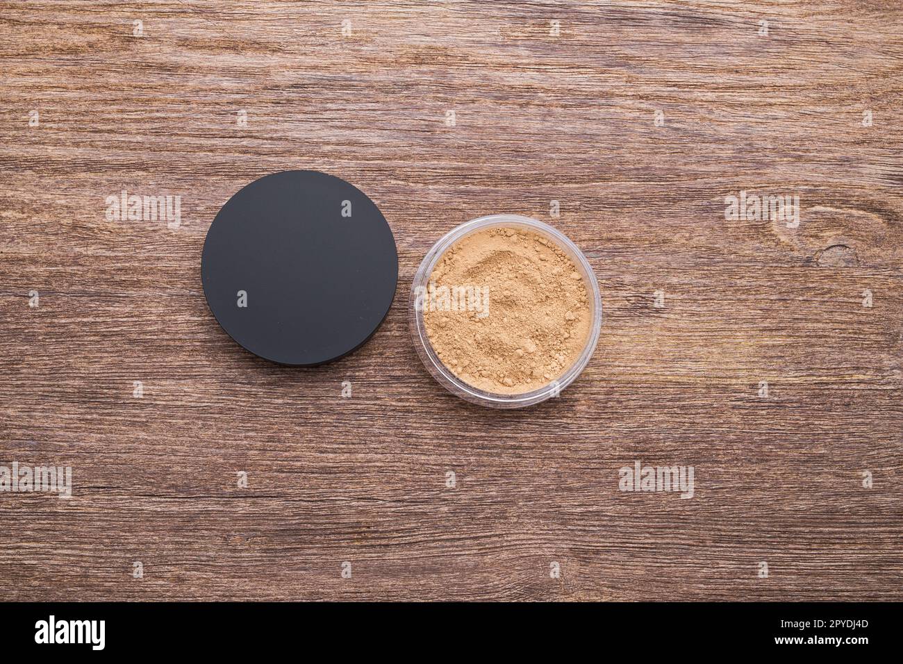 Behälter mit losem mineralischem Gesichtspulver für Hautfarbe auf Holzhintergrund, Nahaufnahme von oben Stockfoto