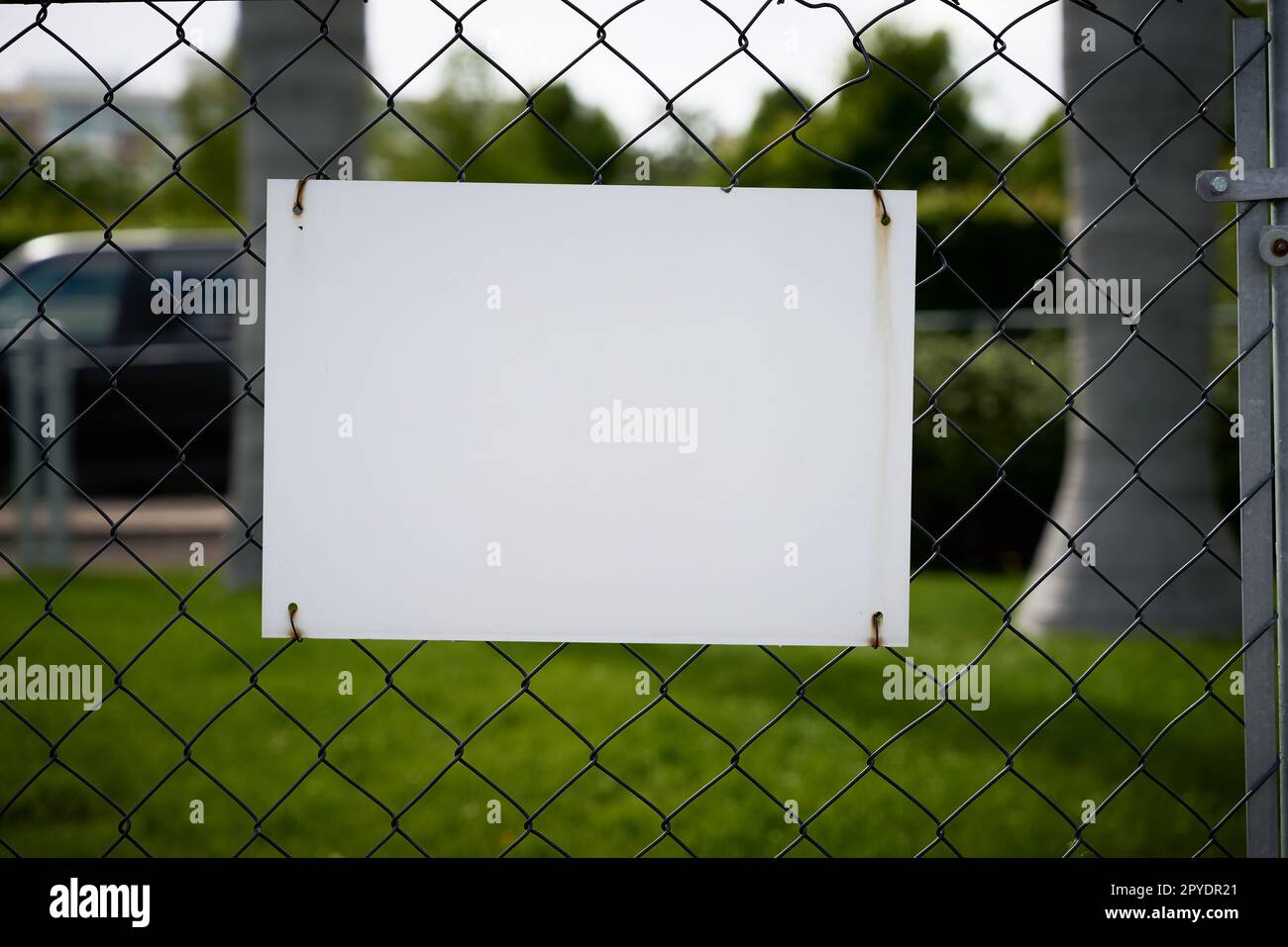Leeres weißes, unbeschriftetes Schild mit Textsperre auf einem Zaun Stockfoto