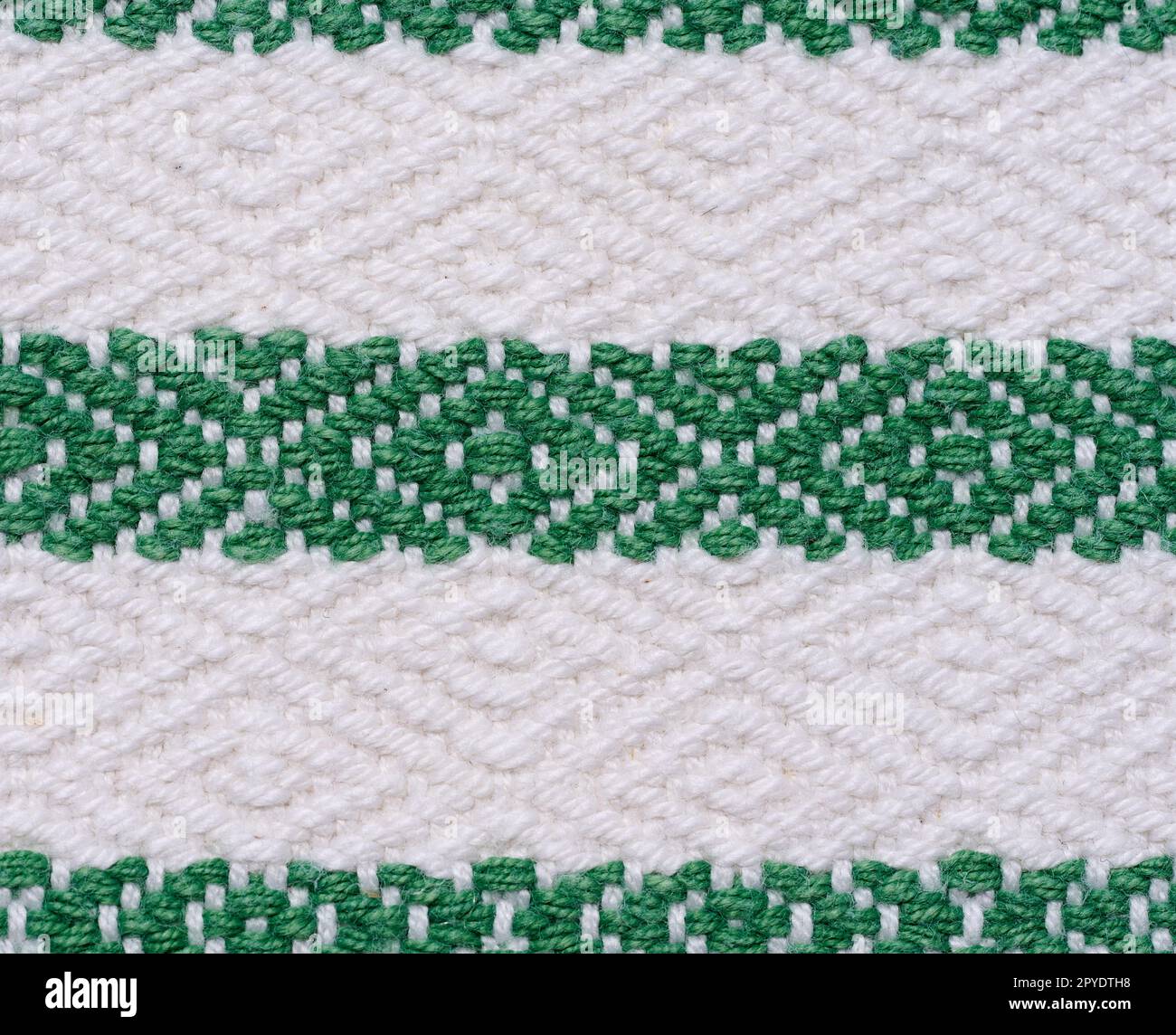 Ein Stück Baumwollstoff zur Herstellung von Tischdecken und Küchenhandtüchern mit grünen Stickerelementen Stockfoto