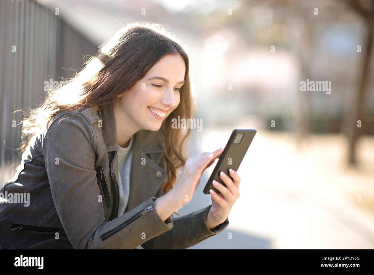 Frau, die Handy benutzt und auf der Straße sitzt Stockfoto