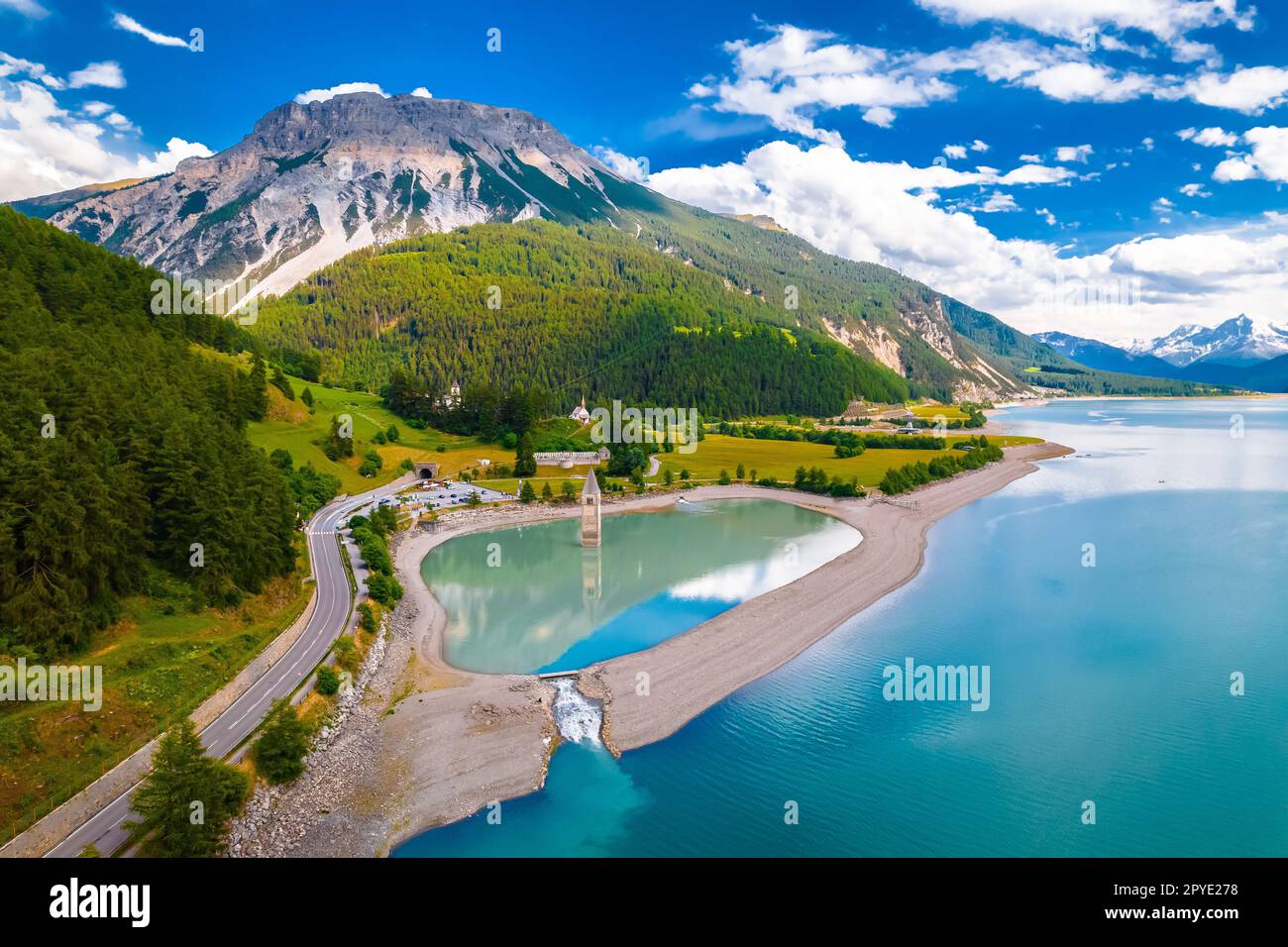 Der untergetauchte Glockenturm von Curon in Graun im Vinschgau auf dem Reschen-See mit Panoramablick auf die Alpenlandschaft Stockfoto