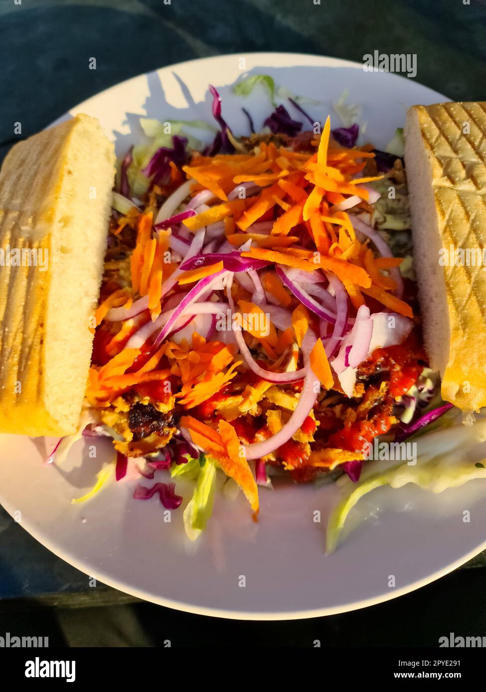 Blick von oben auf einen frischen Kebab-Salat mit zwei Scheiben Brot und Sonnenschein auf dem Teller. Stockfoto