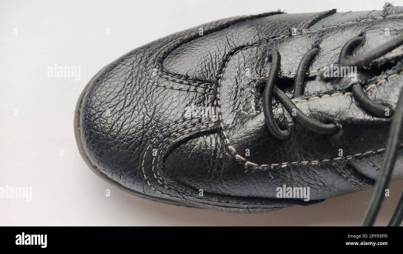 Schwarze Lederstiefel mit Schnürsenkeln. Ein Schuh auf einer grauen Nahaufnahme. Lackiertes echtes Schweinsleder. Saubere Nähte Stockfoto