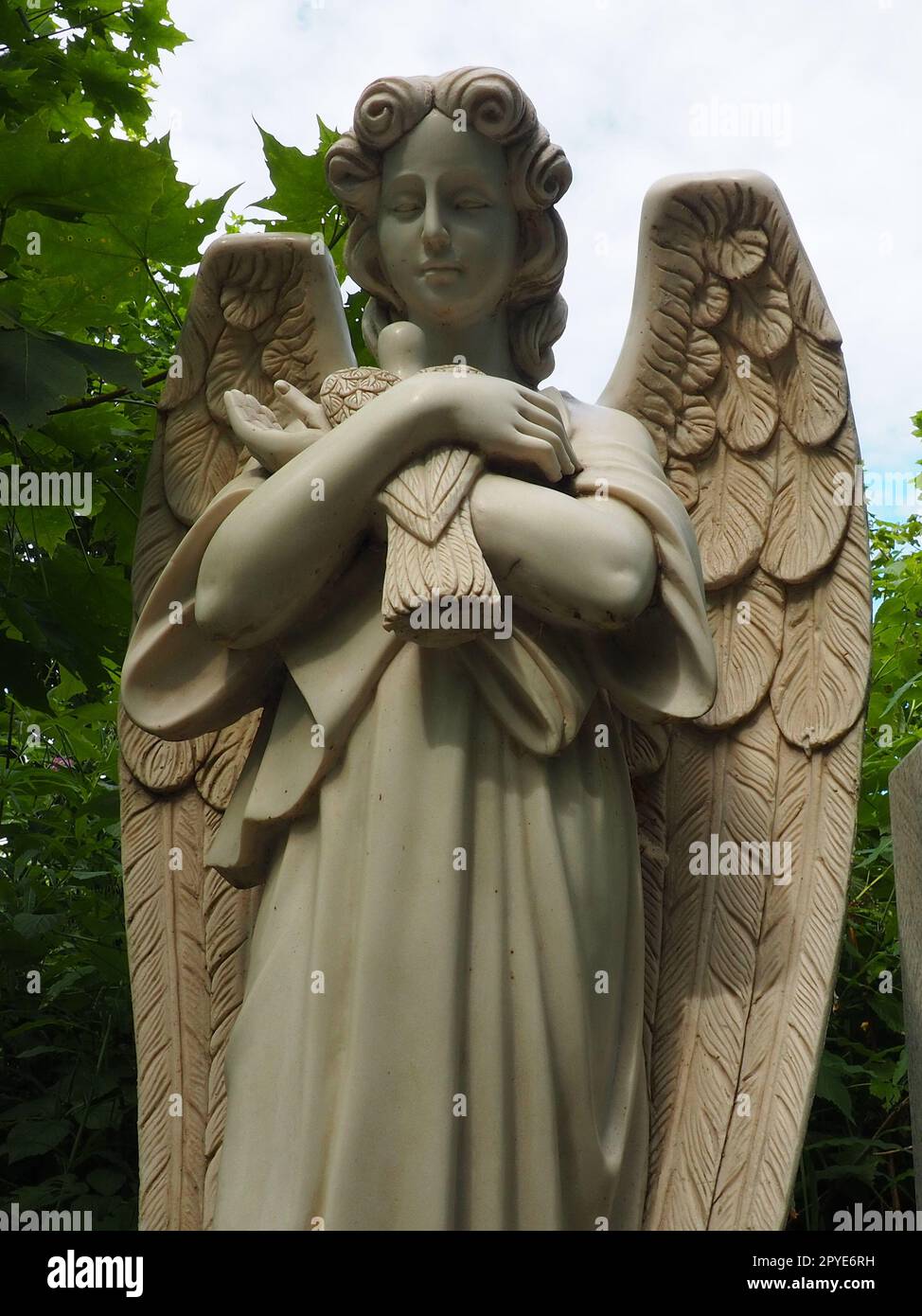 Ein Engel mit einer Taube. Skulptur auf dem Friedhof. Die Gestalt eines Engels mit Flügeln, der einen Vogel in den Armen hält. Klagen für den Verstorbenen. Grabstein-Denkmal auf einem christlichen Grab. Traurigkeit und Trauer Stockfoto