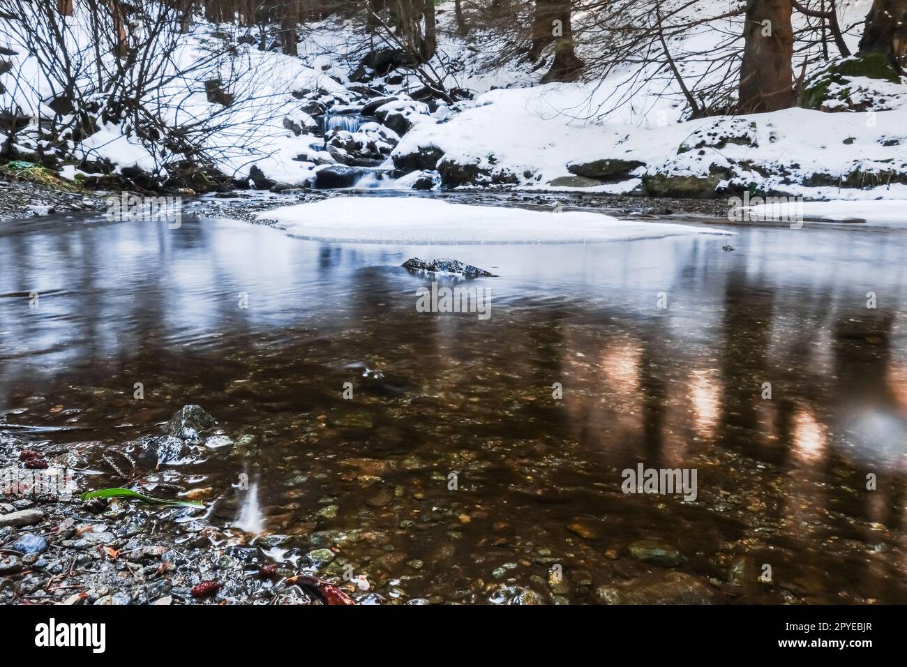 Glatte Wasseroberfläche in einem Bach mit Schnee Stockfoto