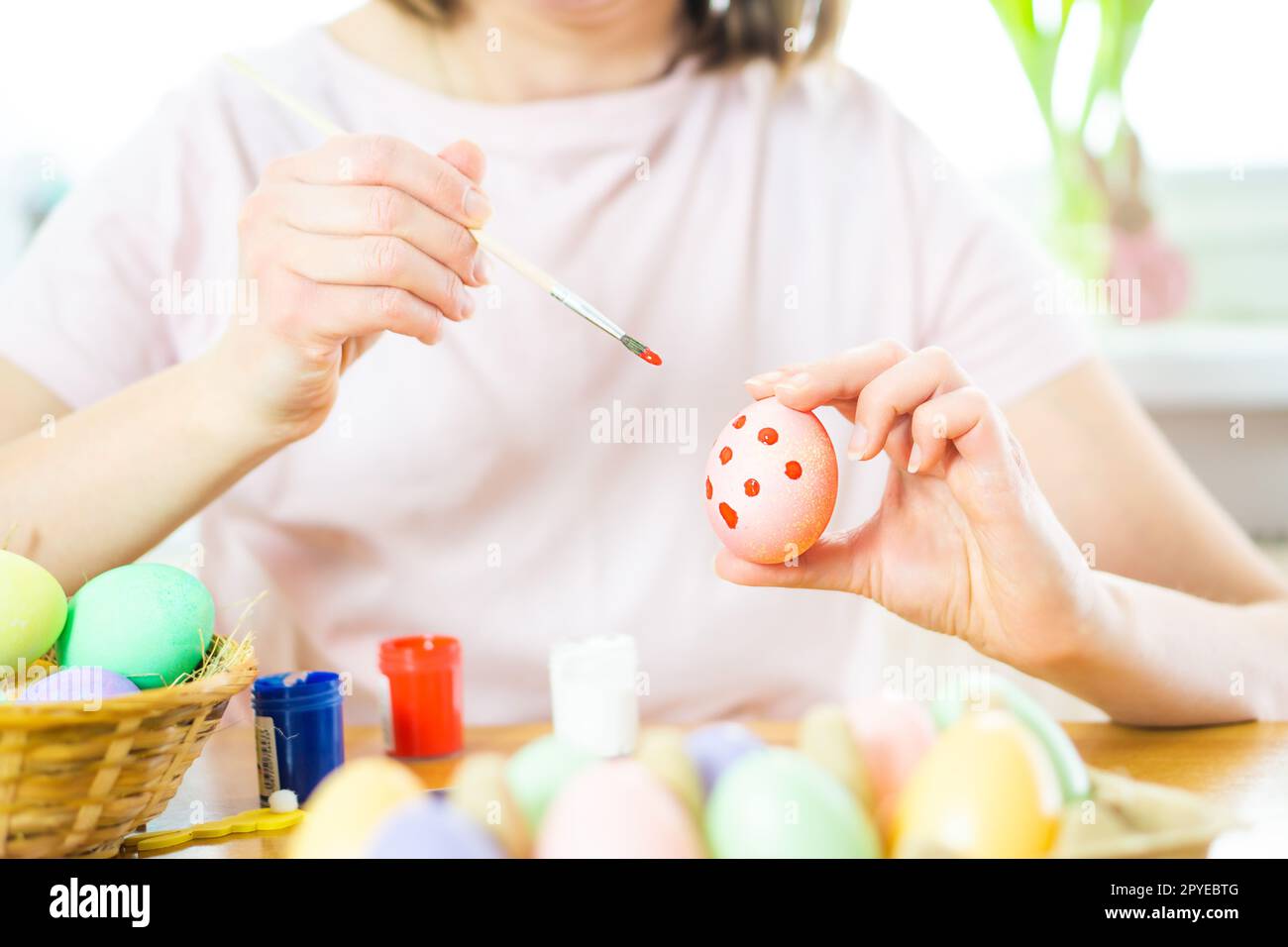 Nahaufnahme von weiblichen Händen, die ein Osterei halten und mit einem Pinsel malen. Vorbereitung auf Ostern Stockfoto