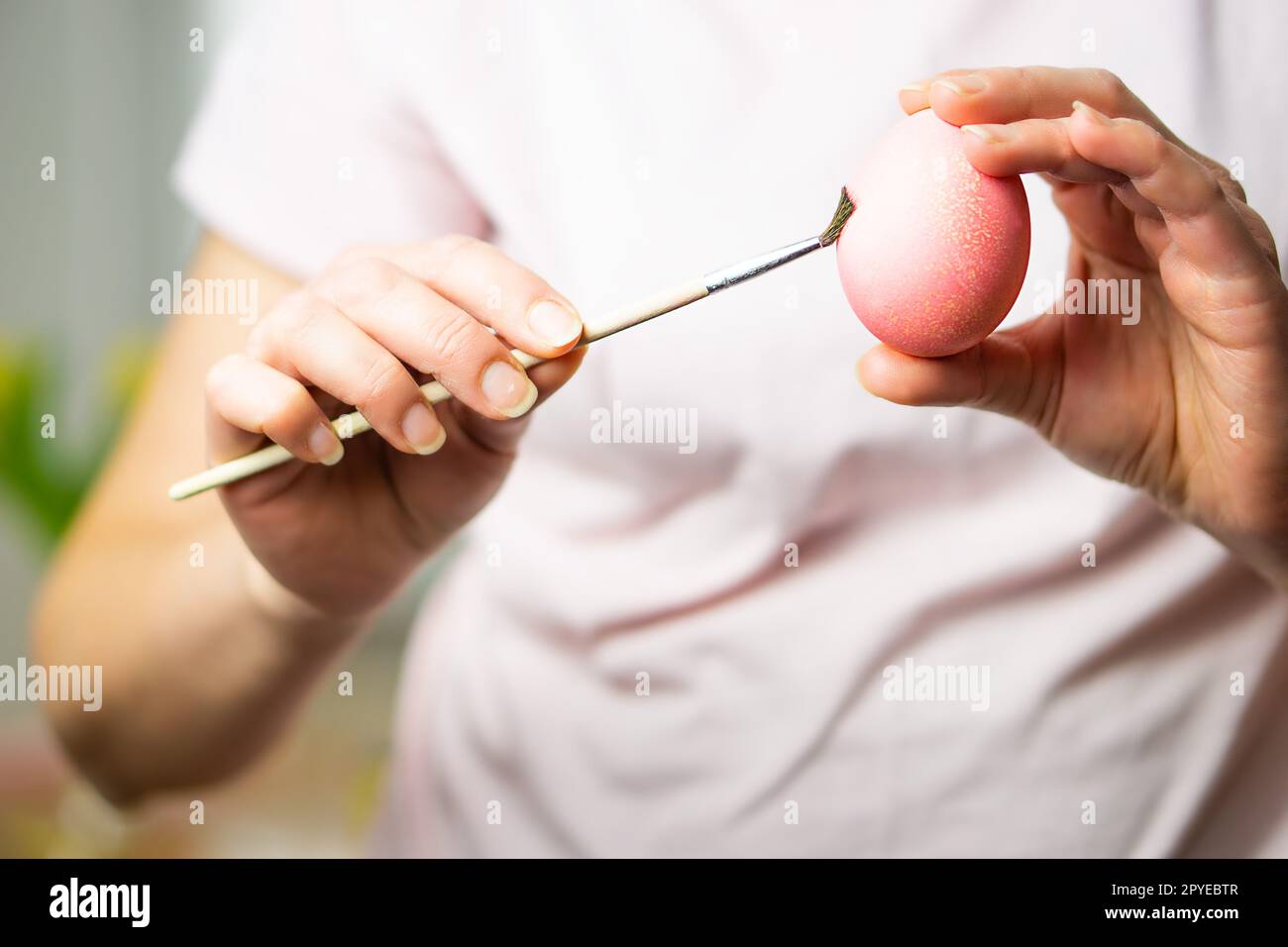 Nahaufnahme von weiblichen Händen, die ein Osterei halten und mit dem Pinsel malen. Vorbereitung für Ostern Stockfoto