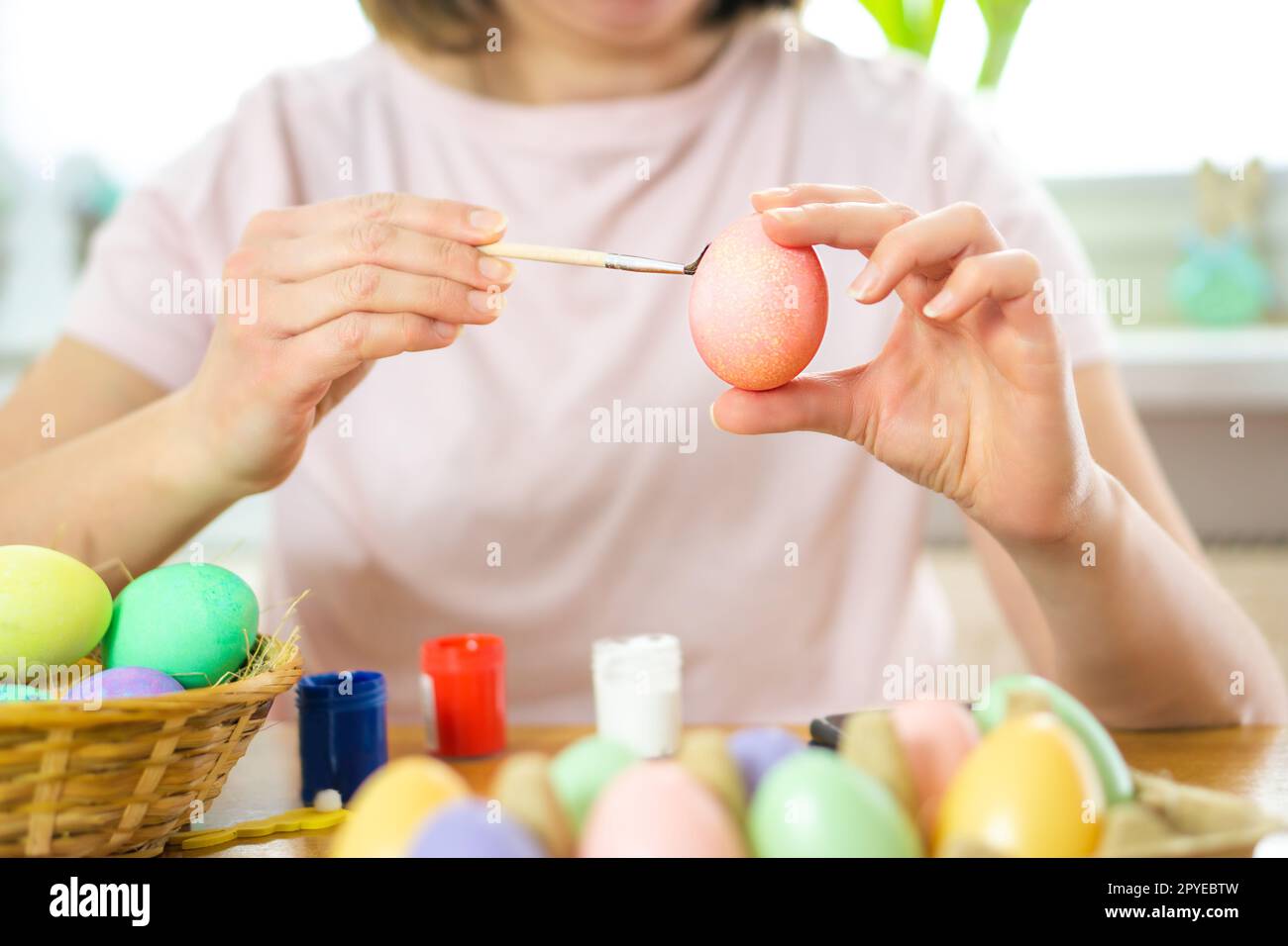 Junge, hübsche Frau malt gerne Ostereier mit den Wasserfarben. Osterfamilientraditionen. Stockfoto