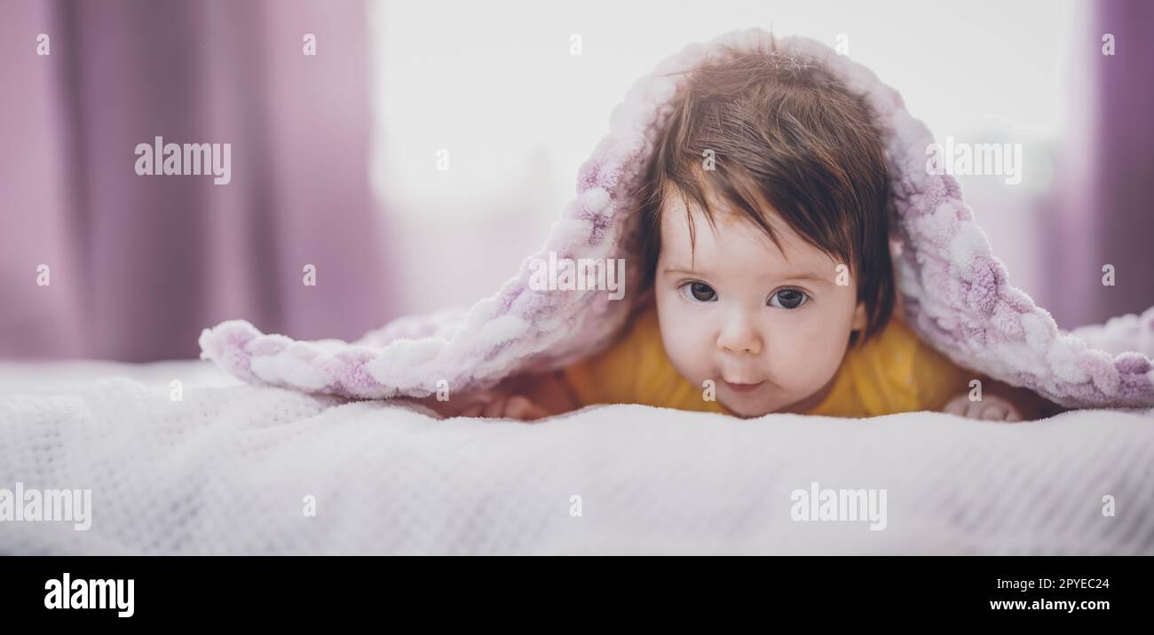 Niedliches kleines Baby, das unter einer rosa Decke liegt. Stockfoto