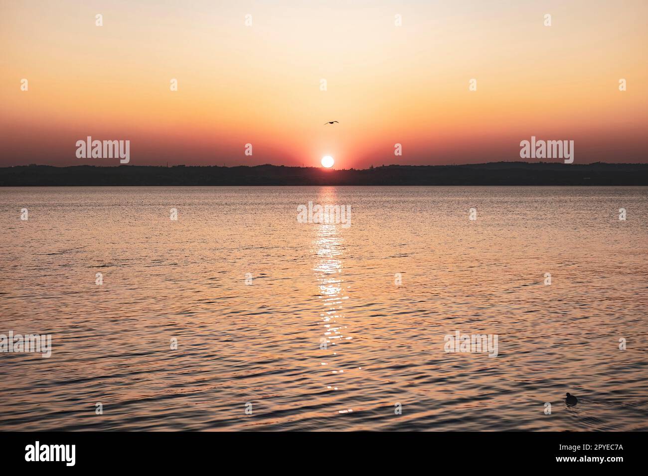 Wunderschöner Sonnenuntergang über dem atemberaubenden Gardasee in Italien, mit der Sonne, die auf dem ruhigen Wasser reflektiert Stockfoto