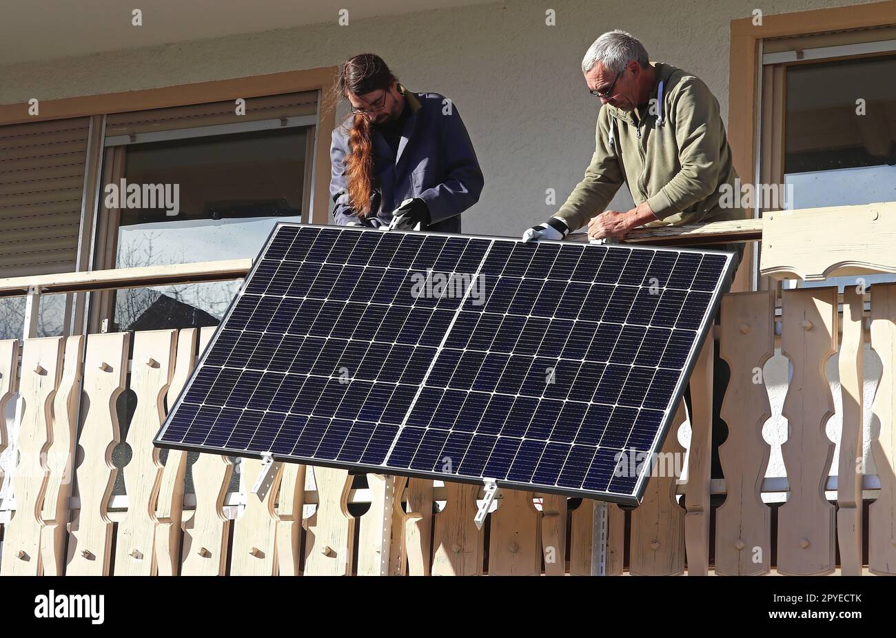 Zwei Männer bauen ein Balkonkraftwerk zusammen, um Strom zu erzeugen Stockfoto