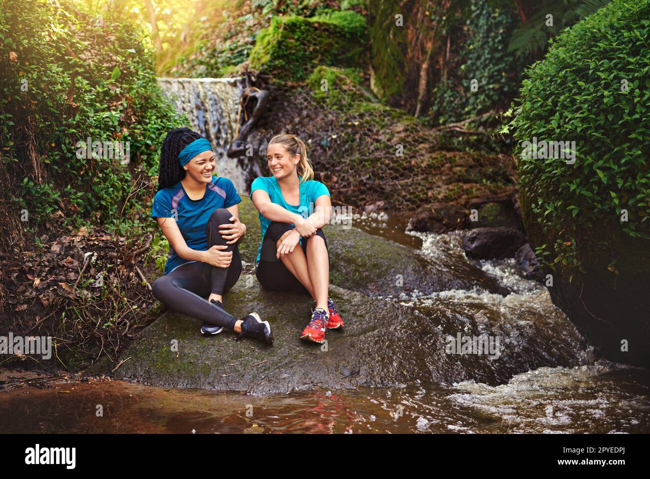 Das Leben ist besser mit einem guten Freund. Zwei sportliche junge Frauen machen eine Pause, während sie in der Natur trainieren. Stockfoto
