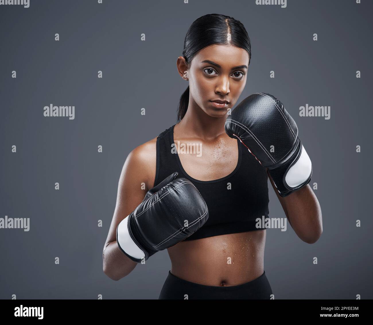 Shell hat dich mit nur einem Schlag umgehauen. Studioporträt einer sportlichen jungen Frau mit Boxhandschuhen vor grauem Hintergrund. Stockfoto