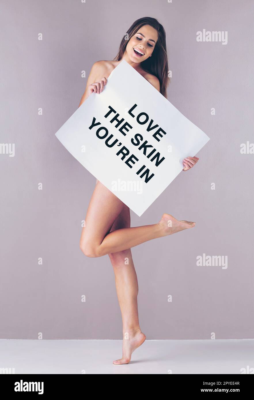 Genieße die Schönheit, mit der du geboren wurdest. Studioaufnahme einer attraktiven jungen Frau mit einem Schild, auf dem "Liebe die Haut, in der du bist" steht, vor einem pinken Hintergrund. Stockfoto