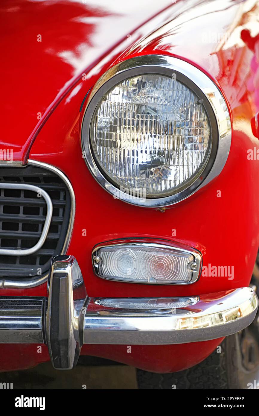 Runde und verchromte Scheinwerfer auf einem roten Oldtimer. Stockfoto