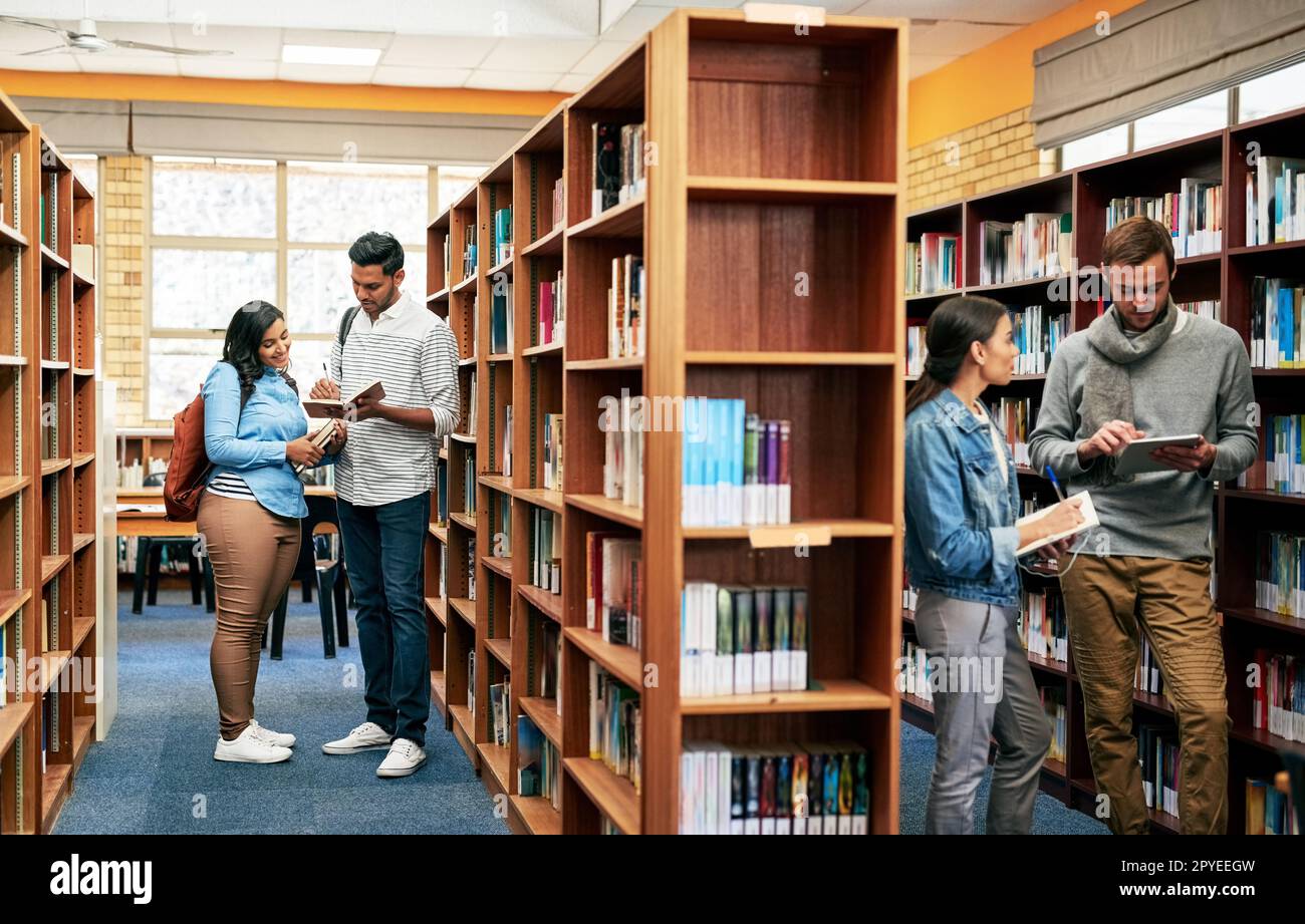 Dort verbringt jeder erfolgreiche Schüler die meiste Zeit. Eine Gruppe von Studenten, die in der Bibliothek auf dem Campus arbeiten. Stockfoto