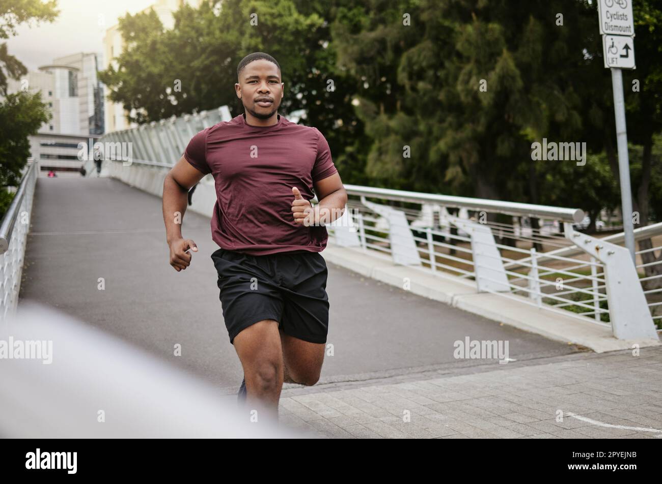Laufen, Fitness und schwarzer Mann auf einer Brücke oder in der Stadt für körperliches Workout, Kardio-Ziele und Marathontraining mit Geschwindigkeit, Energie und Konzentration. Porträt eines Sportläufers auf der straße der usa für ein schnelles Training Stockfoto