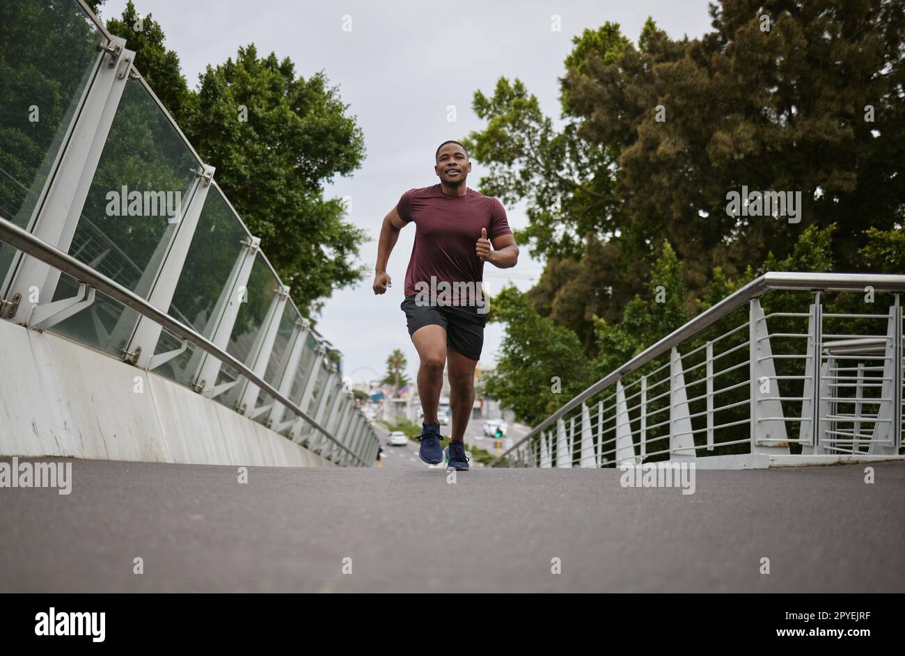 Schwarzer Mann läuft auf einer Brücke in der Stadt für Fitness, Bewegung und gesunde Ziele, Sport Wellness und Marathon-Workout. Urban Runner, Cardio und Training, um Gewicht mit Power, Action und Motivation zu verlieren Stockfoto