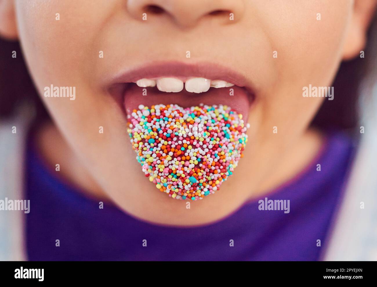 Bringen Sie Farbe in Ihr Leben. Ein unerkennbares kleines Mädchen, das zu Hause mit der Zunge posiert. Stockfoto