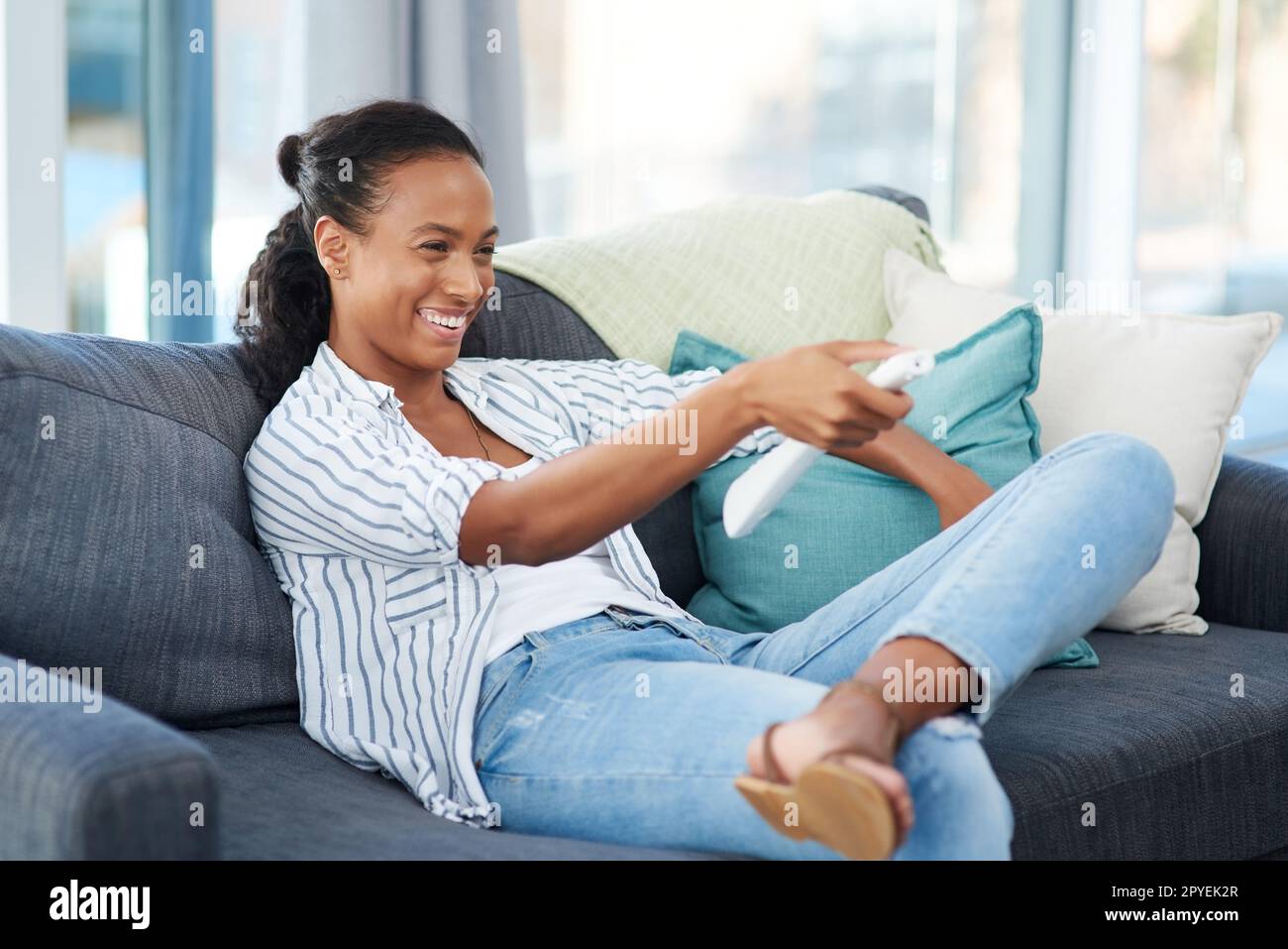 Heute sind es nur ich und der fernseher. Eine junge Frau, die zu Hause fernsieht. Stockfoto