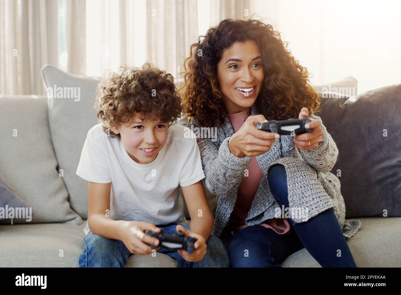 Heute ist Spieltag mit meinem kleinen Champion. Eine junge Mutter und ihr Sohn spielen zu Hause Videospiele. Stockfoto